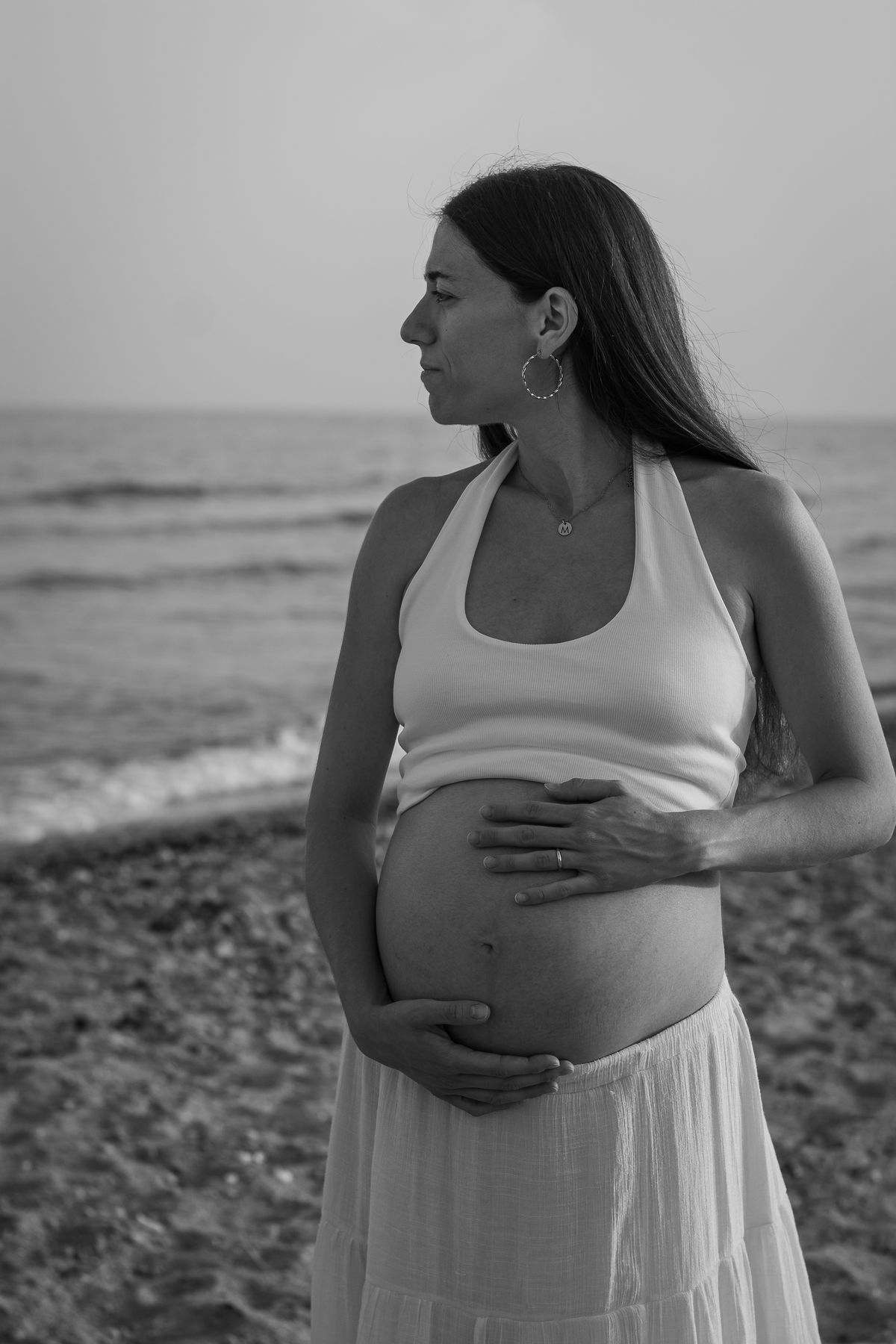 Mujer embarazada de perfil mirando al mar